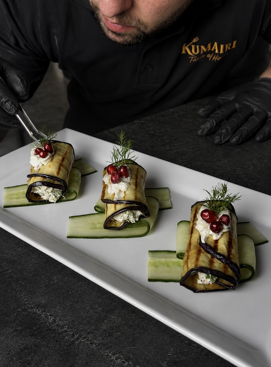 Chef Robert in Kumairi-shirt dresseert aubergine rolletjes met een pincet